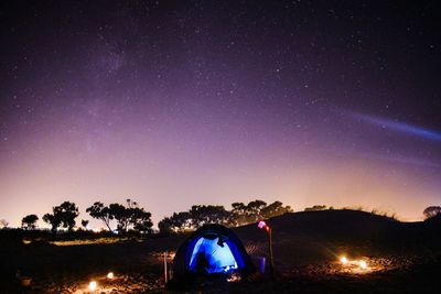 Cars on illuminated road against clear sky at night