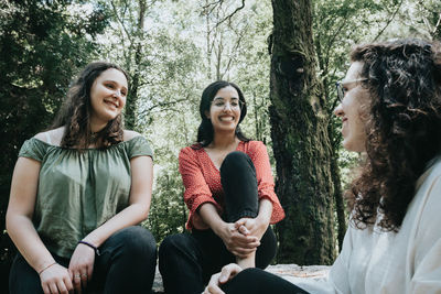 Portrait of smiling friends sitting at park