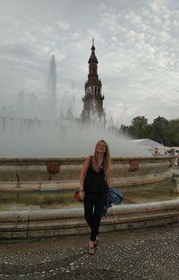 Full length of woman standing against fountain in city