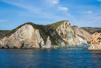 Rock formations by sea against blue sky