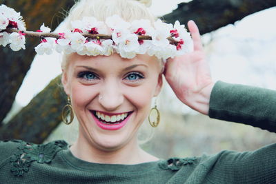 Portrait of smiling woman holding white cherry blossoms