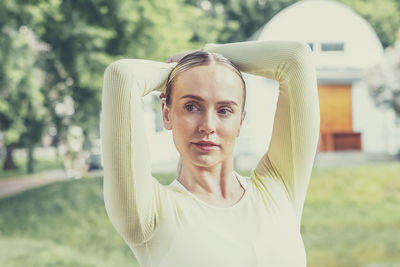 A young beautiful slender girl with long blonde hair does yoga in the summer in nature by the pond