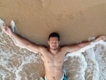High angle view of shirtless man lying at beach