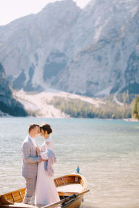 Rear view of couple at lake by mountains