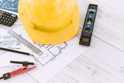 High angle view of various work tools with blueprint on table