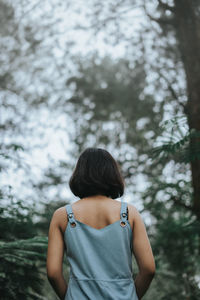 Rear view of woman standing against trees