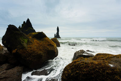 Rock formation on beach against sky