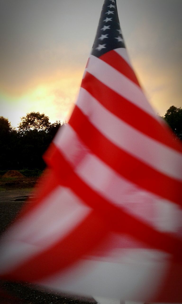 CLOSE-UP OF FLAG AGAINST SUNSET SKY