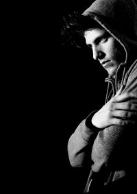 Side view of thoughtful young man looking away against black background