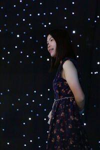 Portrait of a smiling young woman standing at night