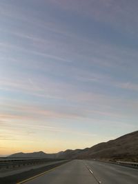 Country road against sky during sunset