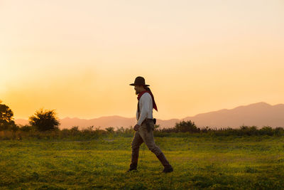 Full length of man standing on field against sky during sunset