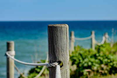 Close-up of wooden post against sea against clear sky