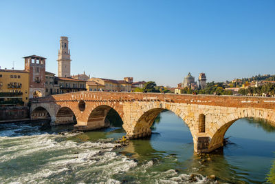 Arch bridge over river against clear sky