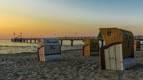 Hooded beach chairs at shore during sunset