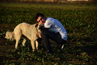 Boy embracing dog on field