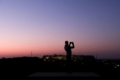 Silhouette man taking photos of jaisalmer during sunrise with smartphone