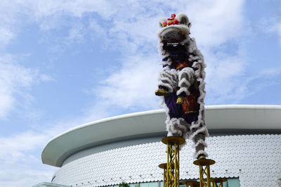 Low angle view of sculpture on pole against sky