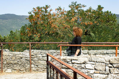 Side view of senior woman standing by tree