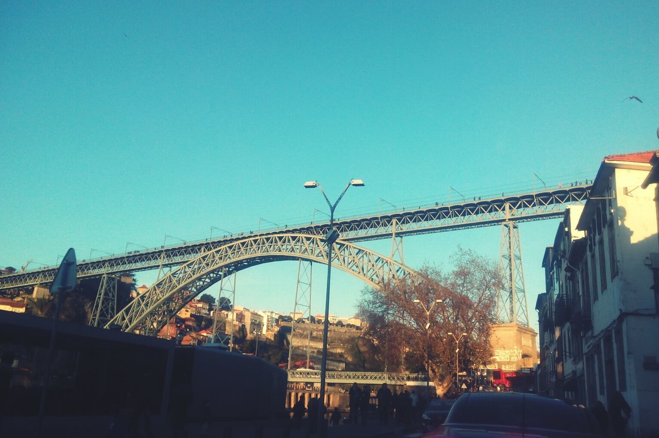 clear sky, built structure, architecture, transportation, copy space, building exterior, car, land vehicle, street light, low angle view, connection, blue, road, mode of transport, street, city, bridge - man made structure, outdoors, sky, incidental people