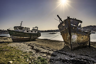 Abandoned boat moored on beach against sky