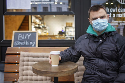 Portrait of man wearing mask standing in cafe