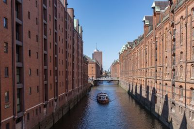 Canal amidst buildings in city against clear sky