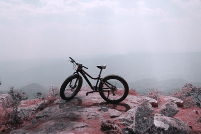 Bicycle on rock against sky