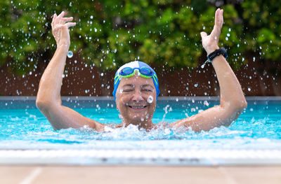 Smiling woman splashing water in swimming pool