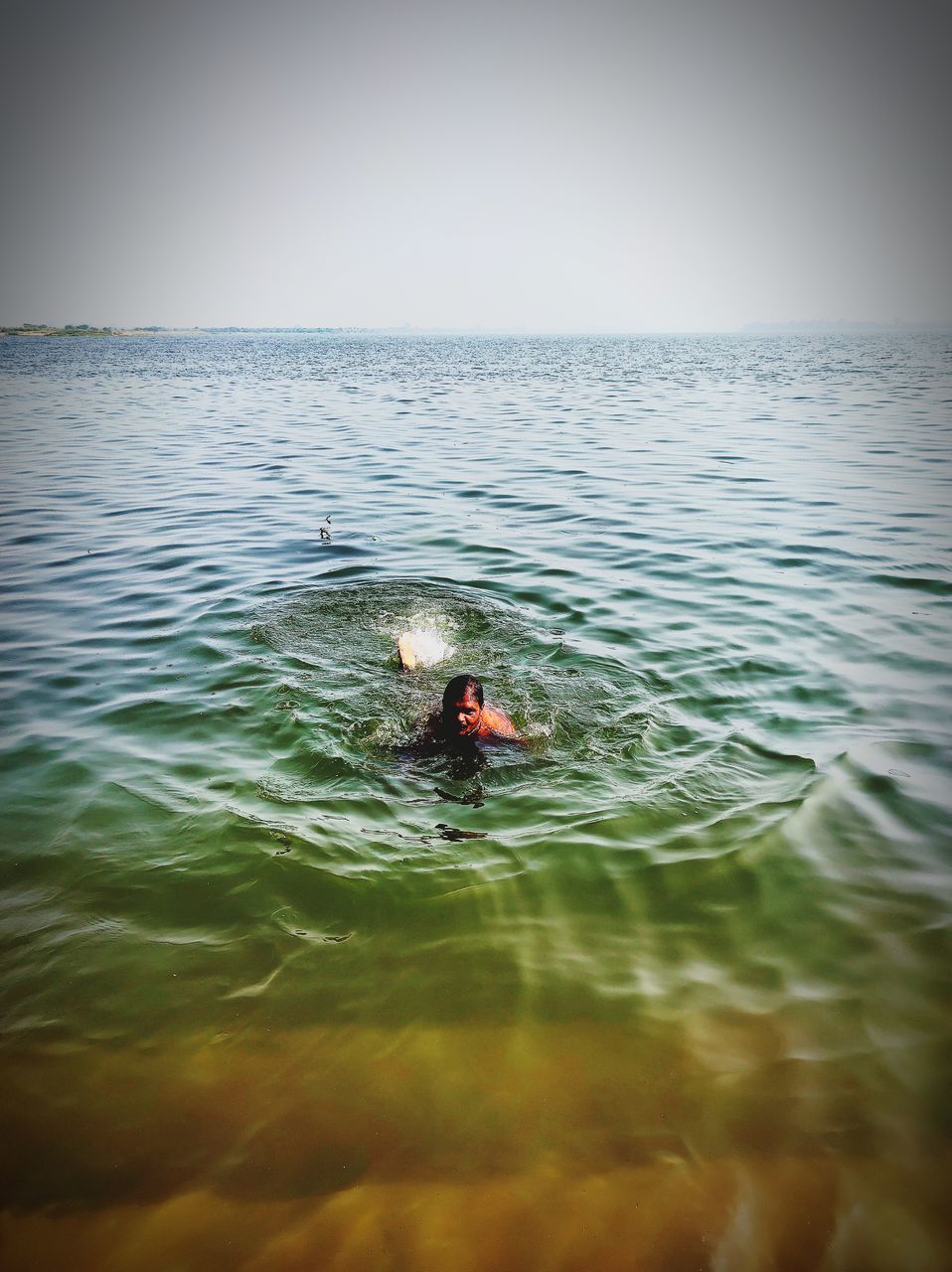 PERSON SWIMMING ON SEA AGAINST SKY