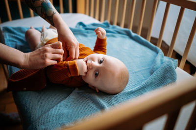 Cropped hand of mother wearing clothes to baby