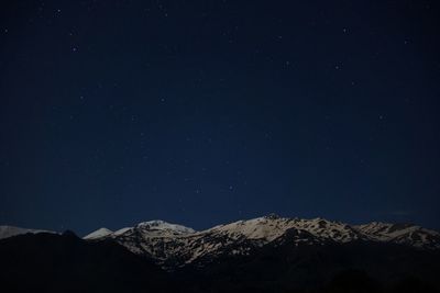 Scenic view of snow covered mountains against sky at night