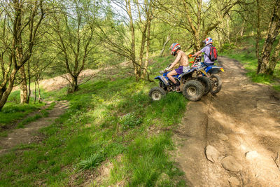 Man riding motorcycle on road amidst trees