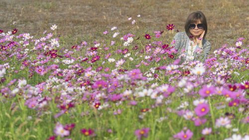 Young woman standing amidst purple cosmos flowering plants on field