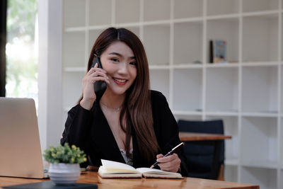 Young woman using phone while standing on table