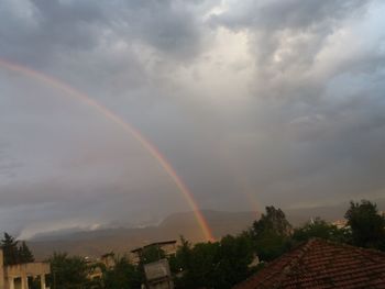 Low angle view of rainbow over buildings against sky