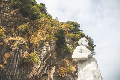 Low angle view of statue against trees against sky