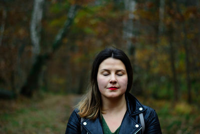 Close-up of beautiful young woman in forest during autumn