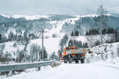 Snow clearing vehicle on snowy mountain road in a winter day