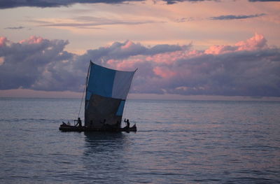 Sailboat sailing on sea against sky during sunset