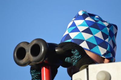 Close-up of person using binoculars against sky