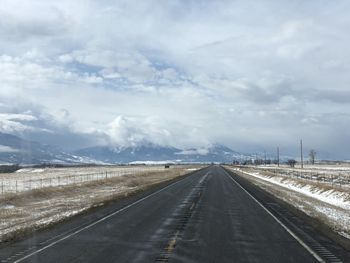 Empty road along snow covered landscape
