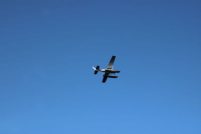 Low angle view of airplane flying against clear blue sky