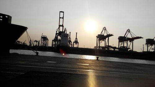 Silhouette of cranes at harbor during sunset