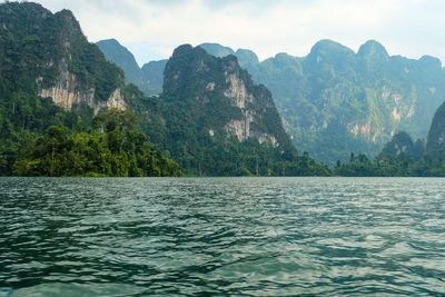 Scenic view of sea by mountains against sky