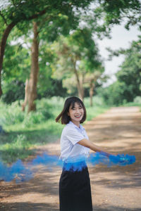 Portrait of smiling woman with smoke torch at park