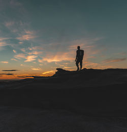 Silhouette man standing on beach against sky during sunset