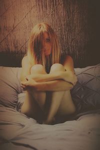 Woman sitting on bed at home