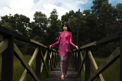 Portrait of smiling woman standing on footbridge