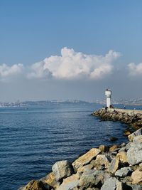 Lighthouse by sea against sky